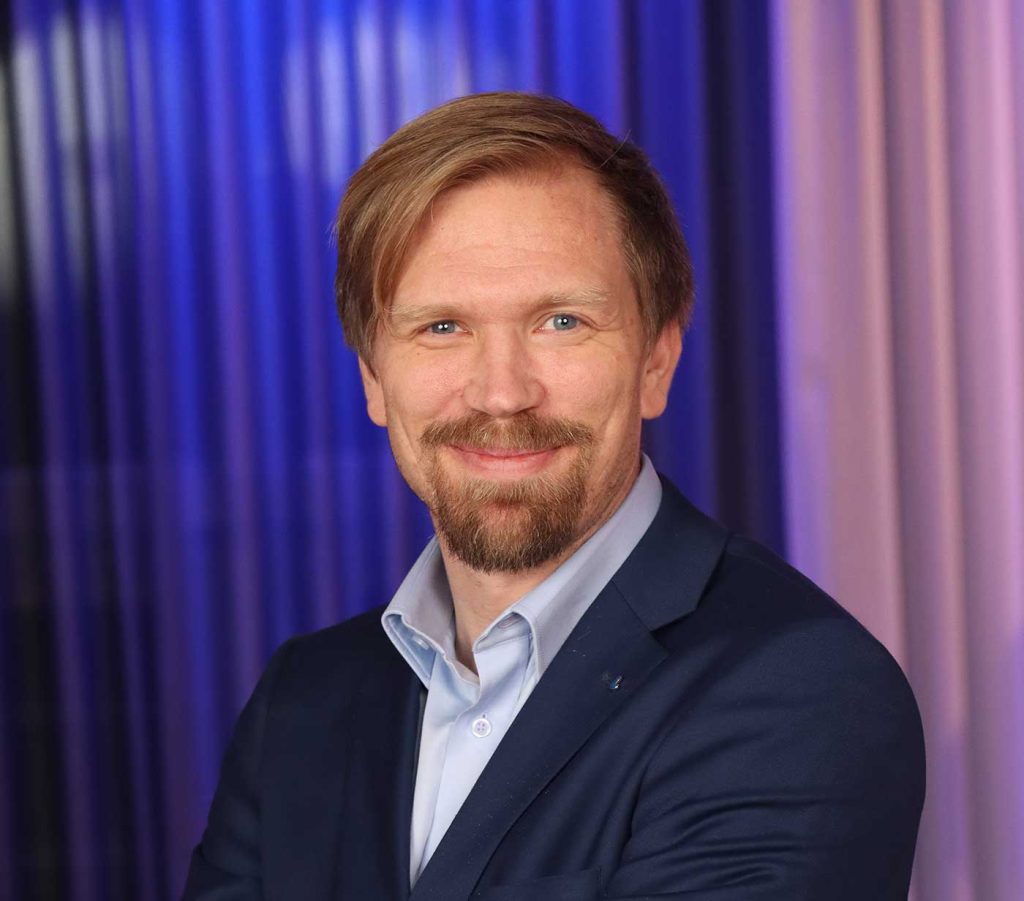 Porträttbild av en leende man i kavaj.