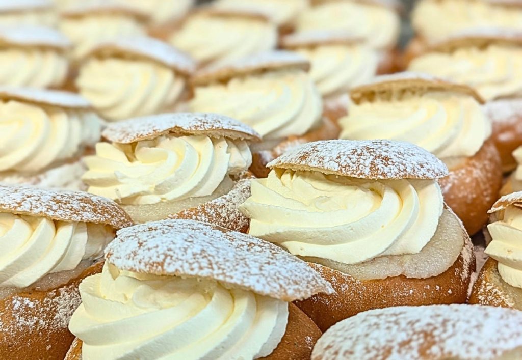 Närbild på många semlor som står tätt intill varandra. 