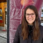 Porträtt av en kvinna som står framför en roll-up med reklam för Arjeplogs Filmfestival.