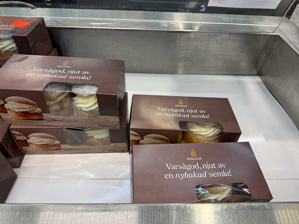 Fyra kartonger med två semlor i vardera. Kartongerna står glest i en kyldisk. Det ser urplockat ut. 