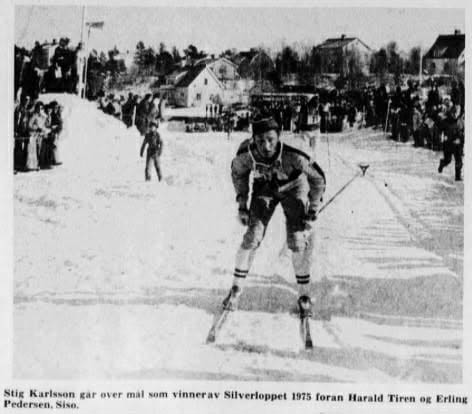 Tidningsurklipp med bild av en skidåkare i förgrunden. I bakgrunden publik och hus. Bildtexten inleds: ”Stig Karlsson går over mål som vinner av Silverloppet 1975...”