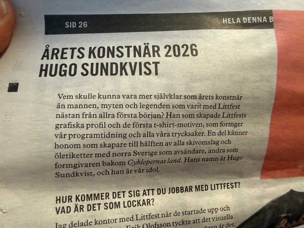 En liten del av en tidningssida. Texten som är orsak till att bilden togs lyder: Årets konstnär 2026 Hugo Sundkvist. Vem skulle kunna vara mer självklar som årets konstnär än mannen, myten och legenden som varit med Littfest nästan från allra första början? Han som skapade Littfests grafiska profil och de första t-shirt-motiven, som formger vår programtidning och alla våra trycksaker. En del känner honom som skapare till hälften av alla skivomslag och öletiketter med norra Sverige som avsändare, andra som formgivaren bakom Cyklopernas land. Hans namn är Hugo Sundkvist, och han är vår idol.